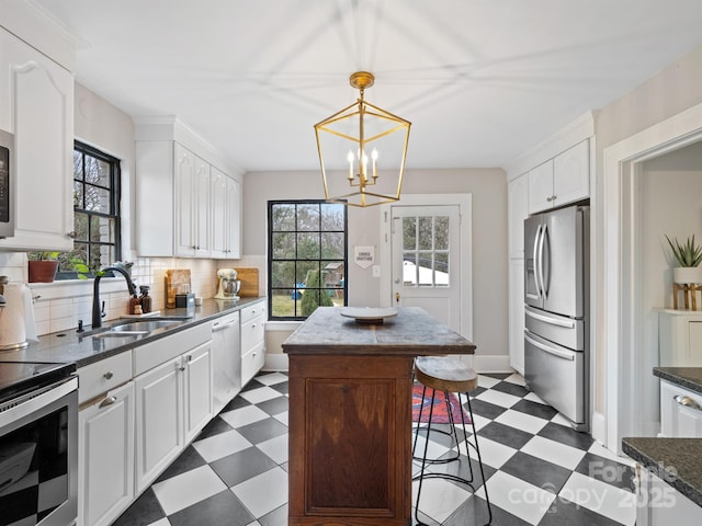 kitchen with sink, a kitchen island, white cabinets, and appliances with stainless steel finishes