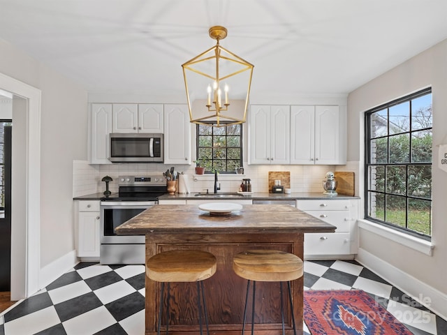 kitchen featuring pendant lighting, sink, white cabinets, stainless steel appliances, and an inviting chandelier