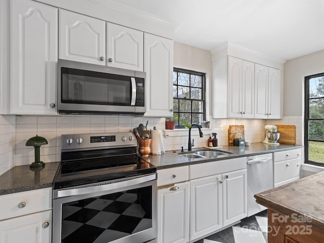 kitchen with stainless steel appliances, sink, white cabinetry, tasteful backsplash, and a healthy amount of sunlight