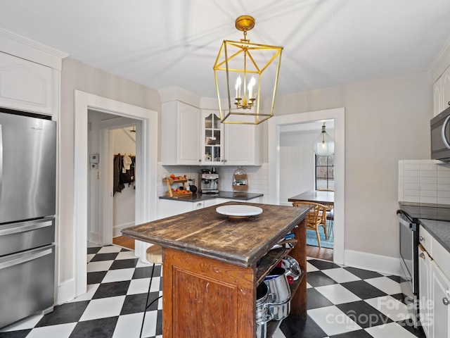 kitchen with appliances with stainless steel finishes, a center island, tasteful backsplash, white cabinets, and a chandelier