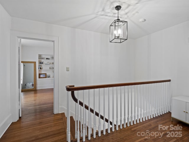 hall with a notable chandelier, dark wood-type flooring, and built in features