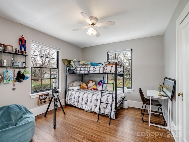 bedroom featuring ceiling fan, wood-type flooring, and multiple windows