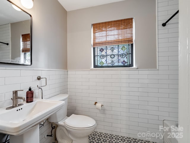 bathroom with walk in shower, plenty of natural light, tile walls, and toilet