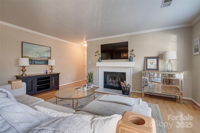 living room with crown molding, a fireplace, and light wood-type flooring