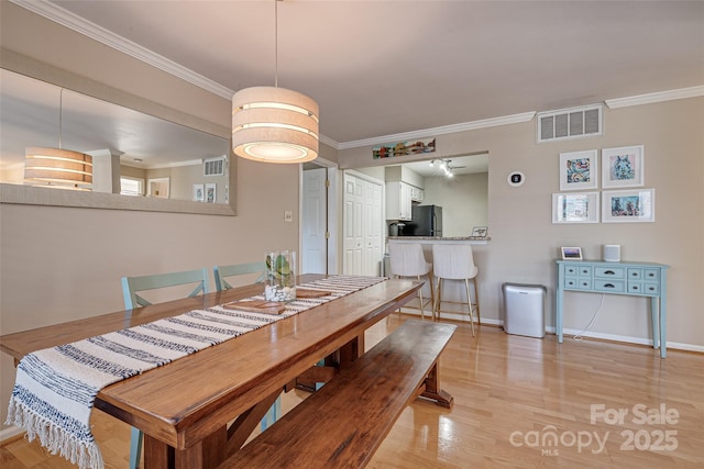 dining area with ornamental molding and light wood-type flooring