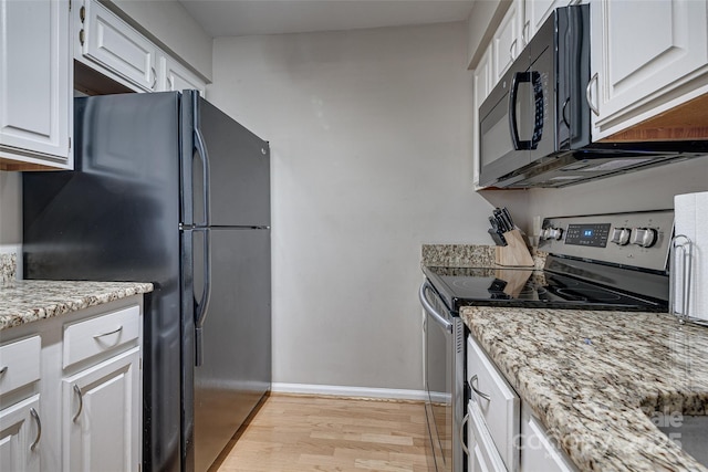 kitchen with white cabinetry, light hardwood / wood-style floors, light stone counters, and black appliances