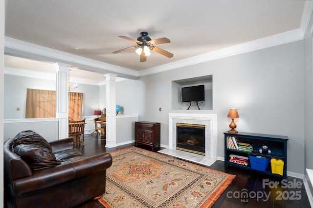 living room with decorative columns, a premium fireplace, dark wood-type flooring, and crown molding