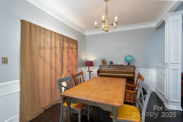 dining area featuring dark hardwood / wood-style flooring, crown molding, a chandelier, and ornate columns