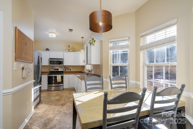 kitchen with pendant lighting, sink, white cabinets, and appliances with stainless steel finishes