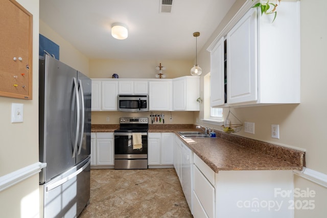 kitchen featuring stainless steel appliances, white cabinetry, sink, and decorative light fixtures