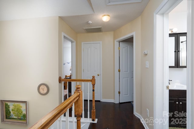 hallway featuring dark hardwood / wood-style flooring, sink, and a textured ceiling