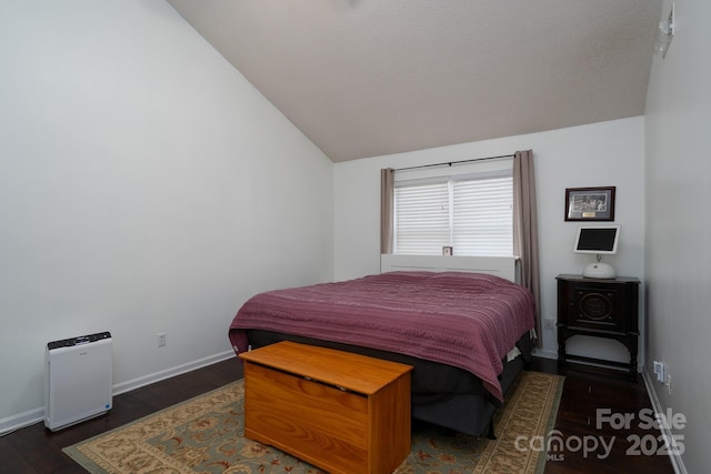 bedroom featuring dark hardwood / wood-style flooring, vaulted ceiling, and a textured ceiling