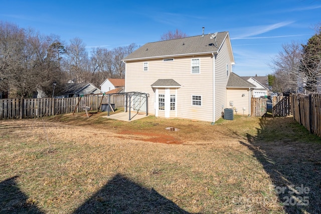 rear view of house with central AC unit, a lawn, and a patio