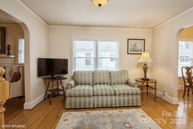 living room with arched walkways, light wood-style floors, baseboards, and ornamental molding