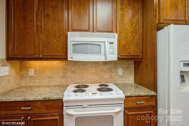 kitchen with brown cabinetry, decorative backsplash, and white appliances