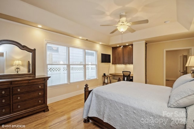 bedroom featuring light wood-style flooring, baseboards, a ceiling fan, and a raised ceiling