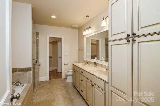 bathroom featuring toilet, double vanity, a sink, and a stall shower