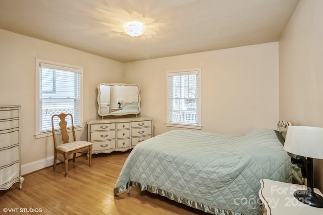 bedroom featuring light wood finished floors and baseboards
