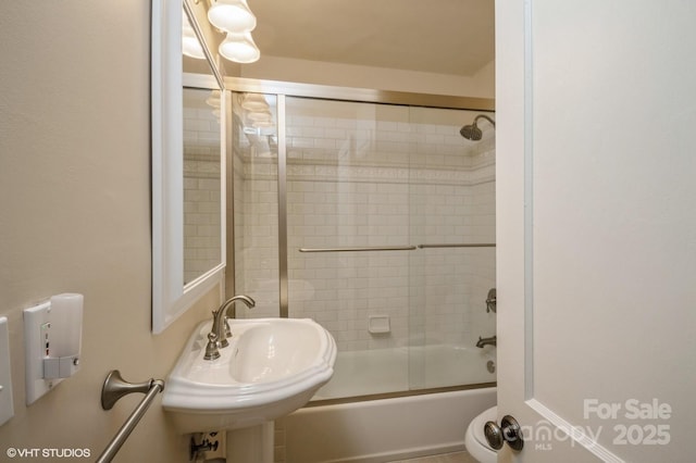 bathroom featuring shower / bath combination with glass door and a sink