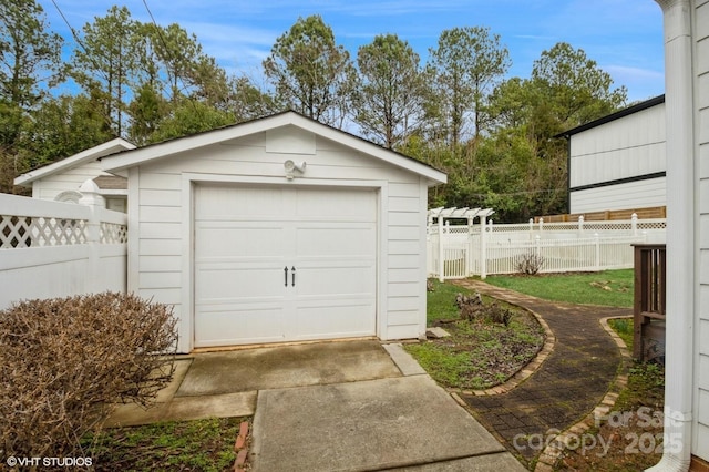 detached garage featuring driveway and fence