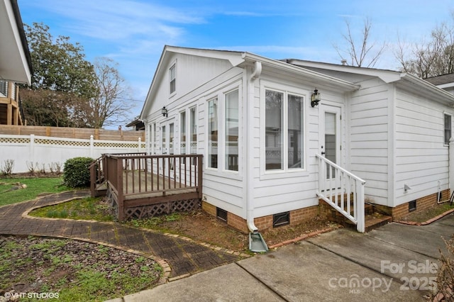 view of side of property with fence, a wooden deck, and crawl space