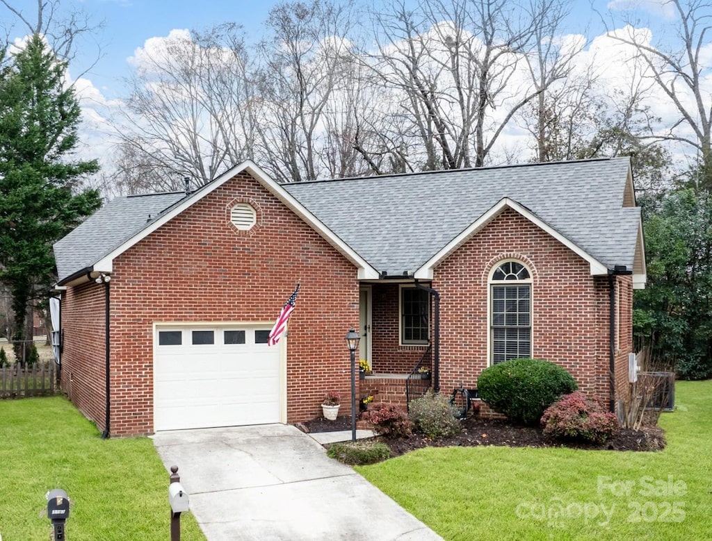 ranch-style home with brick siding, a shingled roof, an attached garage, a front yard, and driveway