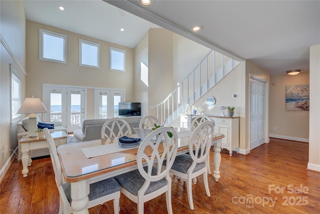 dining area featuring a towering ceiling and wood-type flooring