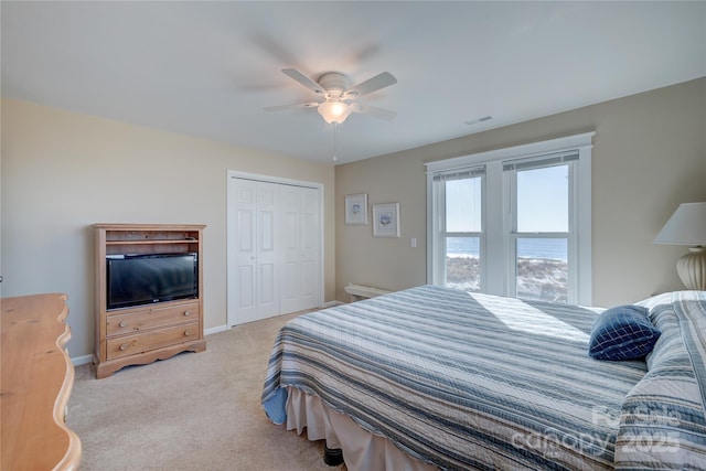 carpeted bedroom featuring a closet, ceiling fan, and a water view