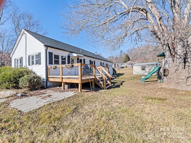 back of house featuring a wooden deck, a playground, and a lawn