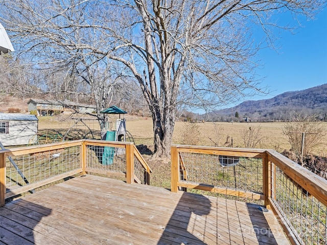 deck featuring a rural view, a mountain view, and a playground