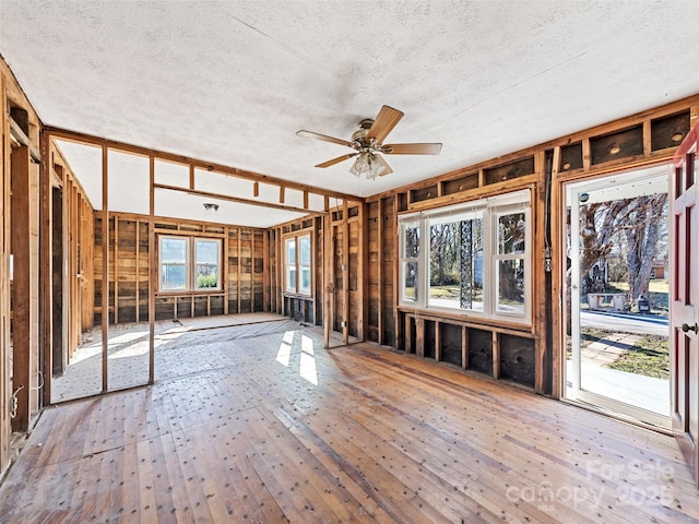 misc room with wood-type flooring, a textured ceiling, and ceiling fan