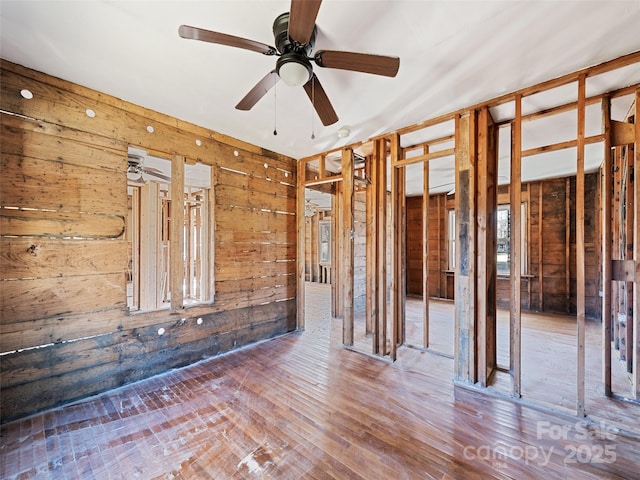 miscellaneous room featuring ceiling fan, hardwood / wood-style floors, and wood walls