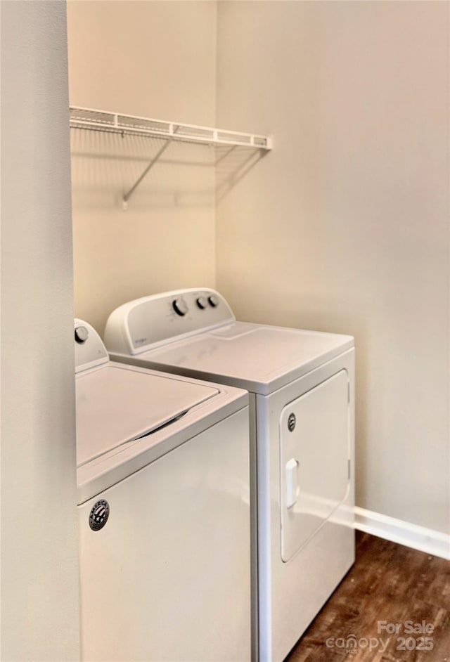 laundry area with laundry area, washing machine and dryer, dark wood finished floors, and baseboards