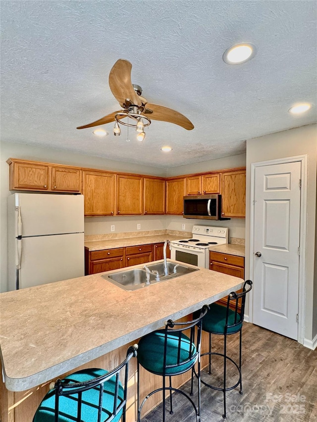 kitchen with light countertops, white appliances, and a center island with sink