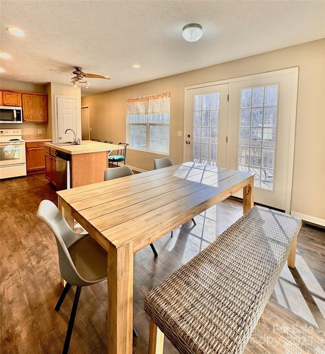 dining space featuring dark wood-style floors, a textured ceiling, baseboards, and recessed lighting