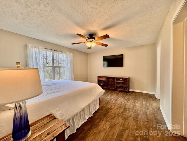 bedroom featuring a textured ceiling, baseboards, dark wood finished floors, and a ceiling fan