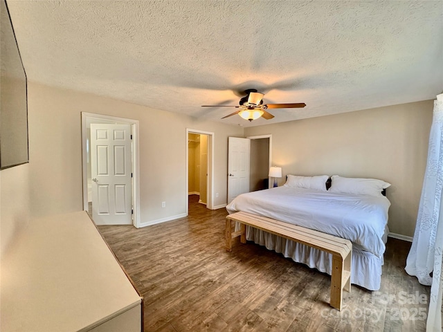 bedroom with dark wood-type flooring, a textured ceiling, baseboards, and a ceiling fan