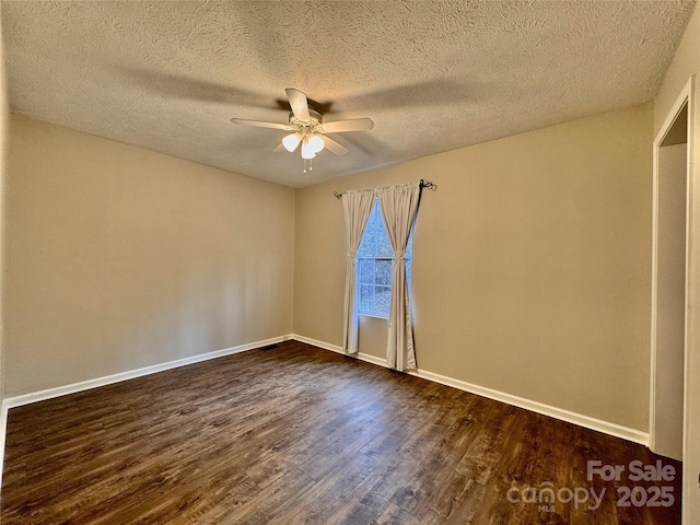 spare room with ceiling fan, dark wood-style flooring, a textured ceiling, and baseboards