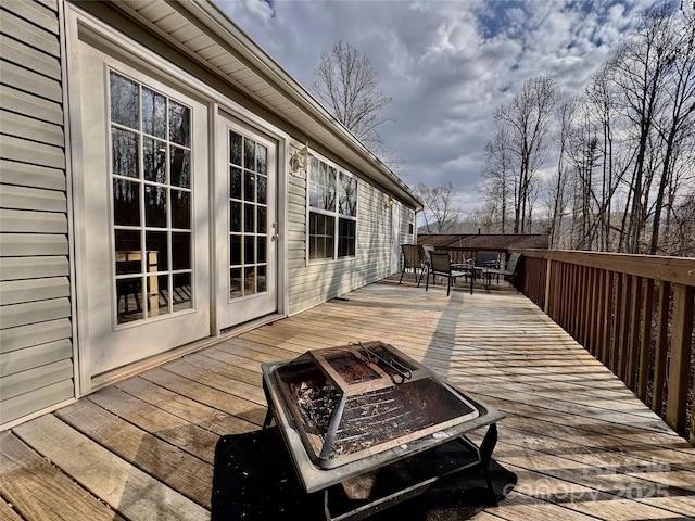 wooden deck with an outdoor fire pit and outdoor dining space