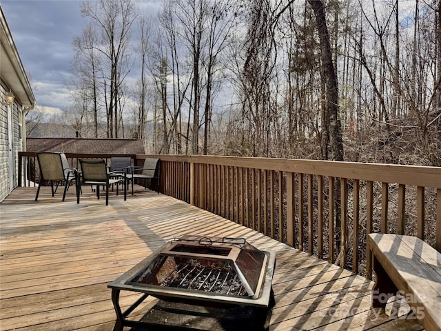 wooden terrace with outdoor dining space and a fire pit