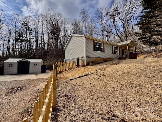 view of property exterior with crawl space, a storage shed, fence, and an outdoor structure