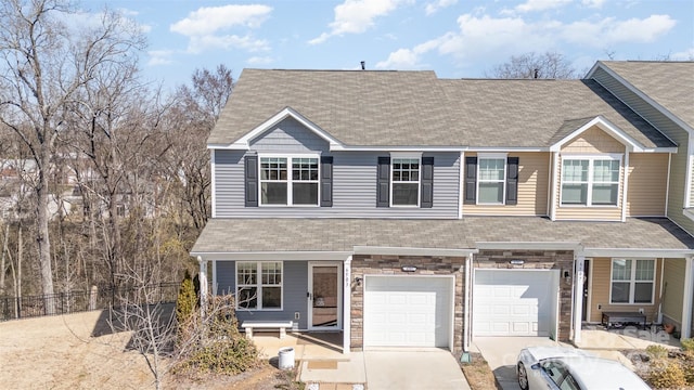 view of front of home featuring a garage, stone siding, driveway, and a shingled roof