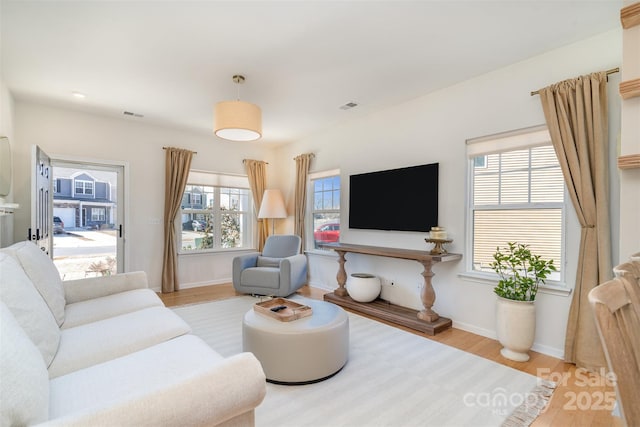 living room featuring light wood-style floors, baseboards, and visible vents