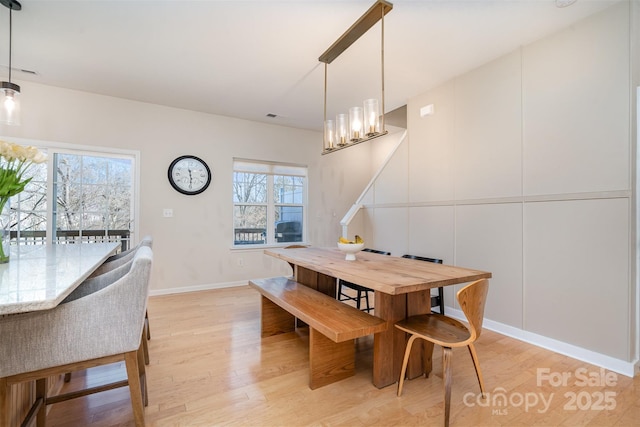 dining room featuring light wood-style floors, a chandelier, a healthy amount of sunlight, and baseboards