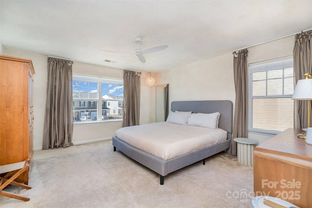 bedroom featuring baseboards, a ceiling fan, visible vents, and light colored carpet