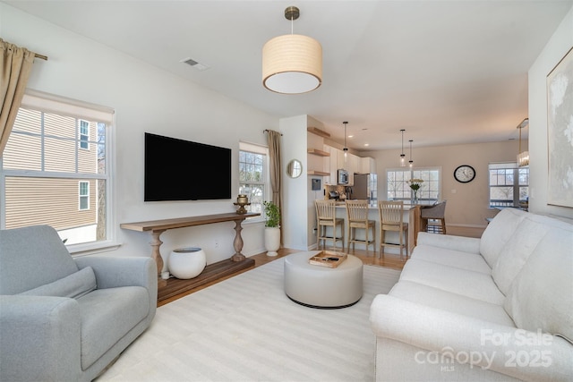 living room with baseboards, visible vents, and light wood-style floors