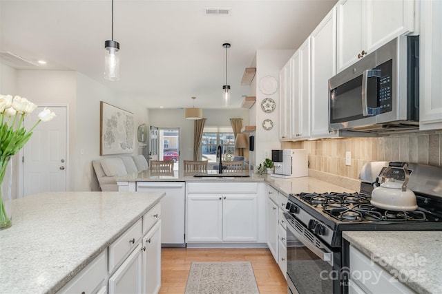 kitchen featuring visible vents, decorative backsplash, appliances with stainless steel finishes, white cabinetry, and a sink