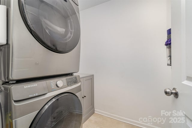 laundry room featuring stacked washer and dryer and cabinet space