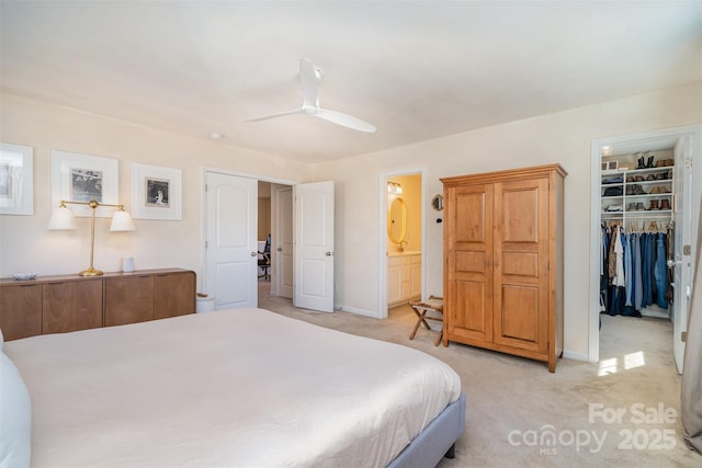 bedroom with light carpet, connected bathroom, a ceiling fan, a spacious closet, and a closet