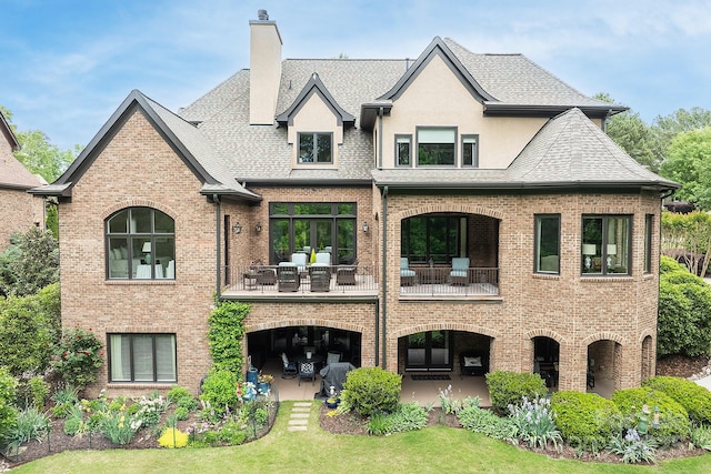 rear view of house featuring a balcony, a yard, and a patio area